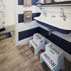 a bathroom with blue and white stripes on the walls, two stools and a sink