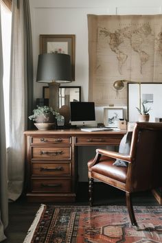 a desk with a chair, lamp and map on the wall above it in front of a window