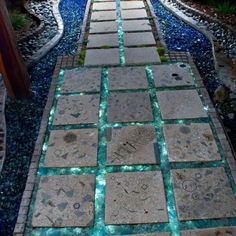 a walkway made out of stone with blue lights on the sides and water running down it