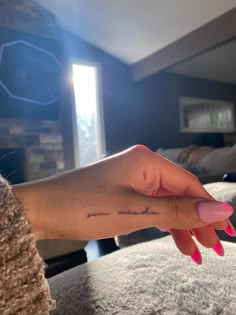 a woman's hand with a small tattoo on her left thumb and the word love is written in black ink