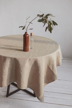 a table with a vase on it and a bottle sitting on top of the table