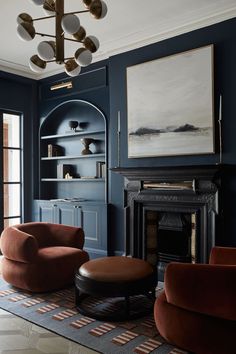 an elegant living room with blue walls and red velvet chairs in front of a fireplace