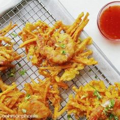 some fried food is sitting on a cooling rack next to ketchup and sauce