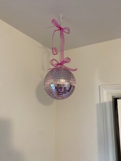 a disco ball hanging from the ceiling with a pink bow