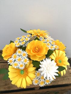 a bouquet of yellow and white flowers sitting on top of a wooden table