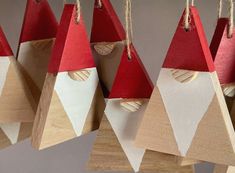 several wooden ornaments with red and white hats hanging from strings on wood hooks, all made out of plywood