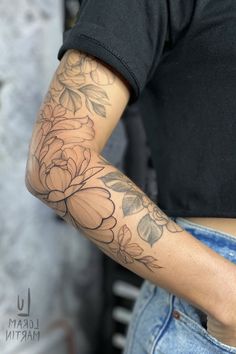 a woman's arm with flowers on it, and a black t - shirt