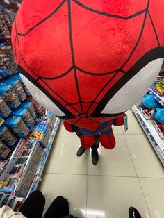 a large red and black spider man balloon in the middle of a grocery store aisle