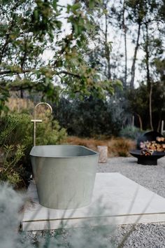 an outdoor bathtub sitting on top of a cement slab next to a fire pit