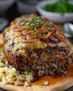 a meatloaf with onions and gravy on a cutting board