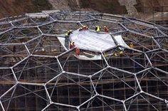 construction workers work on the roof of a large structure