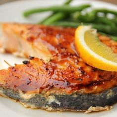 a plate with fish, green beans and lemon wedges