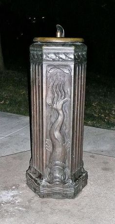 a metal trash can sitting on top of a sidewalk