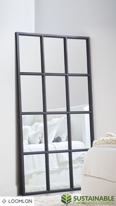 a mirror that is sitting on the floor in front of a white bed and pillows