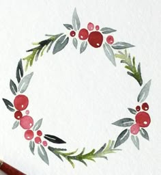 a watercolor painting of a wreath with red berries and green leaves on white paper