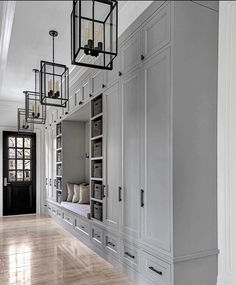 an empty room with white cabinets and wood flooring is pictured in this image, there are lanterns hanging from the ceiling