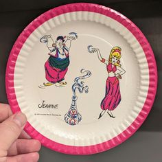 a hand holding a paper plate with cartoon characters on the front and back of it