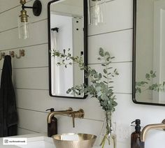 a bathroom sink with two mirrors above it and a vase on the counter next to it