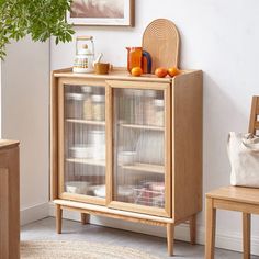 a wooden cabinet sitting next to a potted plant on top of a rug in a living room