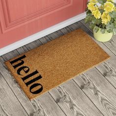 a welcome mat with the word hello written on it next to a potted plant