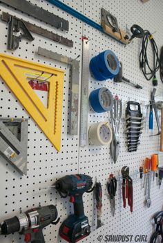 tools are hanging on the pegboard in this garage work area, including drillers, screwdrivers, hammers and pliers