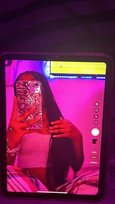 a woman holding a cell phone up to her face in front of a tv screen