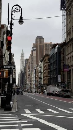 an empty city street with tall buildings and traffic lights on both sides in the distance