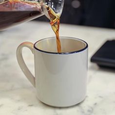 a person pouring coffee into a white cup