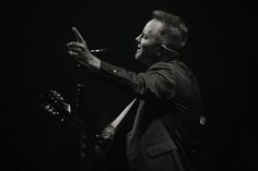 a man in a suit and tie holding a microphone up to the side with his right hand