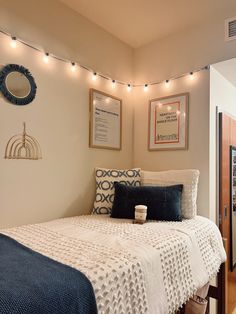 a bedroom with lights strung above it and a bed in the foreground, along with pictures on the wall