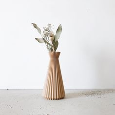 a vase with some flowers in it on a counter top next to a white wall