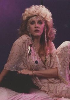 a woman sitting on top of a bed in a white dress and headpieces