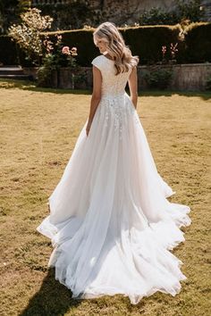 a woman in a wedding dress standing on the grass