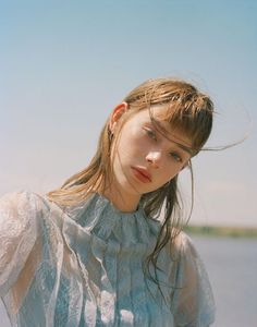 a woman with long hair standing by the water