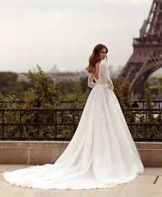 a woman in a wedding dress standing near the eiffel tower