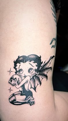 a girl with a bat tattoo on her thigh holding a skateboard in one hand and a skull in the other