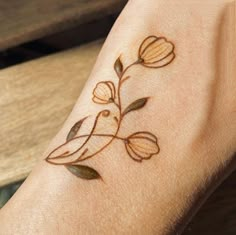 a woman's arm with a bird and flower tattoo design on the left wrist