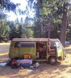 an old camper van is parked in the middle of a field with camping gear