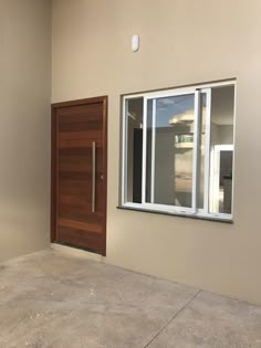 an empty room with a wooden door and window on the wall next to it is concrete flooring