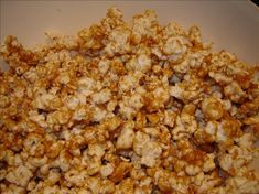 a bowl filled with caramel popcorn sitting on top of a table