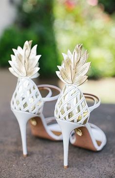 a pair of white shoes with gold pineapple decorations on the toes and heel straps