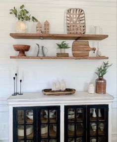 some shelves that have baskets on top of them and plants in vases above them