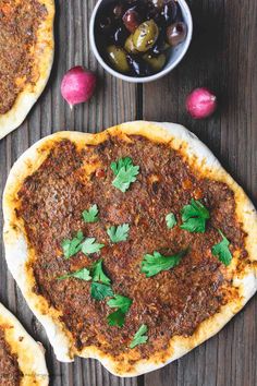 three pizzas sitting on top of a wooden table covered in sauce and toppings