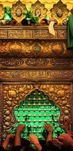 two people standing in front of an ornate wall with green lights and decorations on it