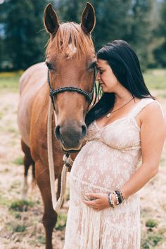 a pregnant woman standing next to a brown horse