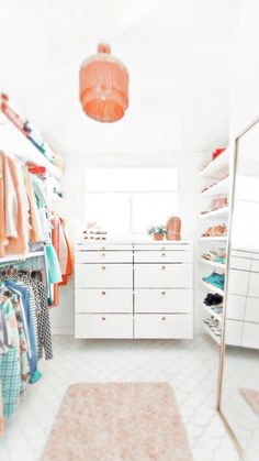 a closet with white drawers and lots of clothes hanging on the walls, along with an area rug