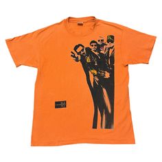 an orange t - shirt with the image of three men on one side and two hands up in the air