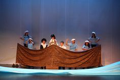 children in striped shirts are on a boat made out of wood planks and fabric