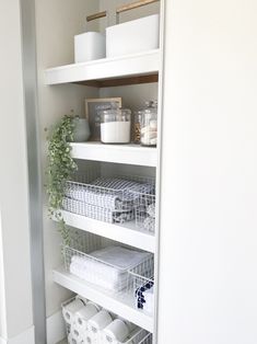 the shelves in this bathroom are organized with baskets, toilet paper and other household items