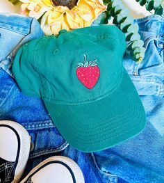 A embroidered strawberry on a green base ball cap. Cute Hats With Embroidered Logo And Curved Brim, Cute Adjustable Brimmed Baseball Cap, Cute Adjustable Baseball Cap, Fun Short Brim Cotton Hats, Playful Adjustable Cotton Baseball Cap, Fun Embroidered Snapback Hats, Fun Hats With Embroidered Logo, Fun Hats With Embroidered Logo One Size, Novelty Cotton Baseball Cap One Size